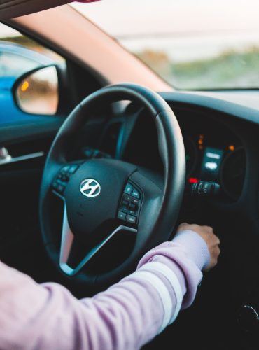 Crop unrecognizable person starting engine in contemporary auto near steering wheel in daylight